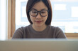© tippapatt - Close up of young asian woman  with eyewear concentrated working on laptop at office. Female student studying online class, searching the information, e-learning