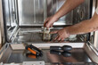 © Nanci - Hands removing a dirty dishwasher filter during diy appliance maintenance, close-up repair scene emphasizing cleaning, efficiency and sustainable household care