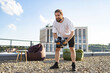 © sofiko14 - A fit man with a beard performs dumbbell exercises on a rooftop terrace with beanbags and a city view