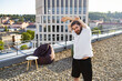 © sofiko14 - A young man performs stretching exercises on a rooftop with a city backdrop in the evening light