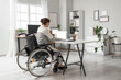 © Pixel-Shot - Young woman in wheelchair working with laptop at office