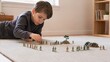 © Bay - Young boy playing with toy soldiers on carpet at home