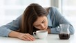 © 69 - Tired young woman in blue shirt resting head on white table with cup of coffee and glass pot, feeling exhausted and sleepy indoors, need caffeine boost