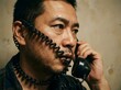 © SITI - Serious middle aged Asian man talking on vintage landline phone with cord wrapped around his face
