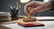 © Hungarian - Close-up of a Hand Holding a Wooden Rubber Stamp Over a Red Ink Pad on an Office Desk for