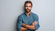 © Glitchmint - Confident man with beard and blue shirt smiling with arms crossed against a gray background