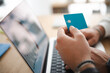 © Studio Marmellata - A person holds a credit card near a laptop, ready to make an online purchase. This image represents digital transactions and modern commerce.