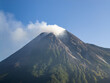 © AmazingAerialAgency - Aerial view of Mount Merapi with smoke rising from the crater and lush green slopes under a clear blue sky Kecamatan Pakem, Daerah Istimewa Yogya, Indonesia.