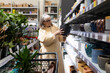 © Ivan Traimak - Mature woman shopping for ceramic flowerpot and plants in a retail store