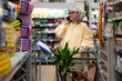 © Ivan Traimak - Senior woman communicating on smartphone while buying plants and garden supplies in a retail store