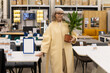 © Ivan Traimak - Mature woman holding potted plant while shopping for home decor