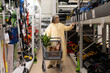 © Ivan Traimak - Woman selecting gardening equipment and tools from shelves in a retail hardware store aisle