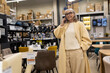 © Ivan Traimak - Mature woman talking on phone while shopping for furniture in a store
