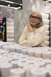 © Ivan Traimak - Senior woman browsing wallpaper rolls, planning home renovation and decor