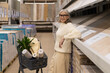© Ivan Traimak - Senior woman smiling while leaning on a display of wood flooring samples in a hardware store