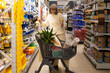 © Ivan Traimak - Woman standing in hardware store selecting paint brushes for a diy home improvement project