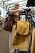 © Ivan Traimak - Senior woman considering a shopping trolley bag in a retail store