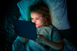 © Volodymyr - Kid facing tablet light in bed at night. Teenager lying in bed watching tablet at night.