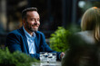 © Zoran Jesic - Smiling man having business conversation at outdoor cafe