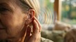 © Kristina - Woman wearing modern hearing aid device. Solution for hearing loss with digital sound wave visualization. Innovative medical technology for health improvement and sensory aid communication.