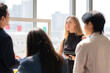 © NT_studio - Caucasian businesswoman holding tablet presenting financial report on glass board, colleague team listening during modern office meeting, collaboration and teamwork during project brainstorming.