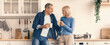 © Prostock-studio - Two people are standing in a modern kitchen, smiling and holding coffee cups. They are having a joyful conversation while standing by the countertop decorated with kitchen items.