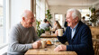 © Xenia - Two happy elderly Caucasian men drinking coffee and laughing in cafe. Senior friends sitting at table enjoying conversation and pastry during social meeting