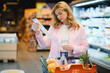 © Serhii - Woman checking long grocery receipt in supermarket
