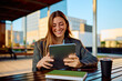 © we.bond.creations - Professional young businesswoman smiling while working with a digital tablet on an outdoor terrace, showcasing modern business, technology, and career success in a relaxed environment