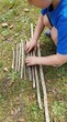 © Yauhen - Child organizes and measures wooden sticks on grass with an old ruler. Montessori style outdoor education and nature exploration. Ideal for educational blogs or parenting content.