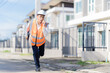 © MrAshi - A male civil engineer or construction supervisor, wearing a yellow safety helmet and reflective vest, is on a construction site, representing a real estate development concept for a housing constructi