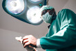 © chokniti - Doctor surgeon surgery hospital operating surgical mask light healthcare professional doctor green surgical gown bright operating light focused patient care and modern hospital environment