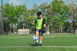 © chokniti - World cup concept with soccer ball or football player, young boy playing soccer on green field outdoors with focused expression and blue ball