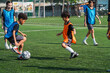 © chokniti - World cup concept with soccer ball or football player, youth soccer game on outdoor field with children in training bibs, active play and teamwork