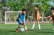 © chokniti - World cup concept with soccer ball or football player, young children playing soccer on green field with goal and trees in sunny outdoor park