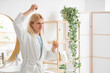 © Pixel-Shot - Young blonde man applying hair serum in bathroom