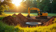 © miss irine - Yellow excavator digs hole for septic tank installation in rural field. Construction machinery works on site during golden hour sunlight. Earth piled around concrete ring.