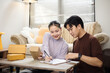 © vittaya - Asian Couple Managing Small Business Orders and Analyzing Sales Data Together at Home