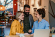 © La Famiglia - Business colleagues meeting, laughing, and discussing work in a cafe