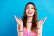 © deagreez - Happy young woman looking up with joyful expression wearing colorful beaded jewelry against bright blue background