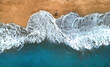 © helivideo - AERIAL, TOP DOWN: Unrecognizable surfer walking along the exotic sandy beach.