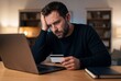 © Meow Creations - Stressed Man Looking at Laptop Holding Credit Card During Online Payment Problem