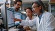 © forenna - Genomics laboratory manager trains a new clinical bioinformatics analyst at a sequencing data visualization workstation in a molecular pathology department, pointing to somatic variant filtering par