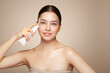 © Oleg Gekman - Beautiful woman with bottle of moisturizer cream. Video of woman with perfect skin on beige background. Beauty and Skin care concept