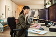 © Marko Geber - Woman software developer coding on dual monitors in modern office