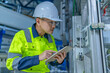 © reewungjunerr - Asian electric engineer holding clipboard for checking and monitoring the electrical system in the control room,Technician thailand people working