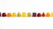 © Riola - Colorful, diverse shaped gummy candies in a precise linear arrangement, captured with bright studio lighting for nutritional product promotion.