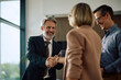 © Drazen - Happy insurance agent shaking hands with couple after successful meeting in office.