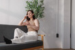 © Phimwilai - Woman talking on mobile phone relaxing on sofa