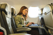 © SISMIZ - Woman working on laptop inside airplane cabin during flight